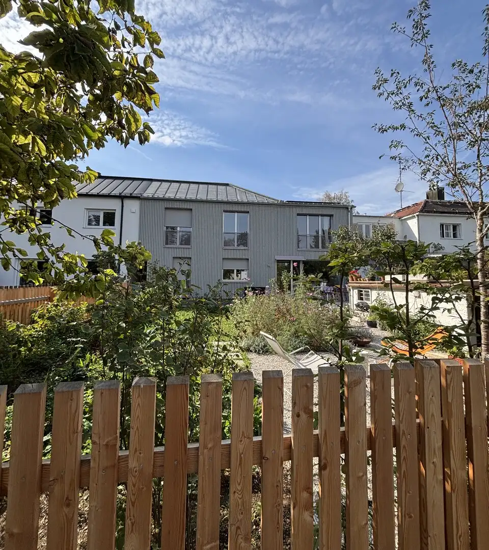 SOLL-Zustand: dasselbe Haus nach der Sanierung mit neuer Fassade und neuem Dach, Gartenseite im Sommer